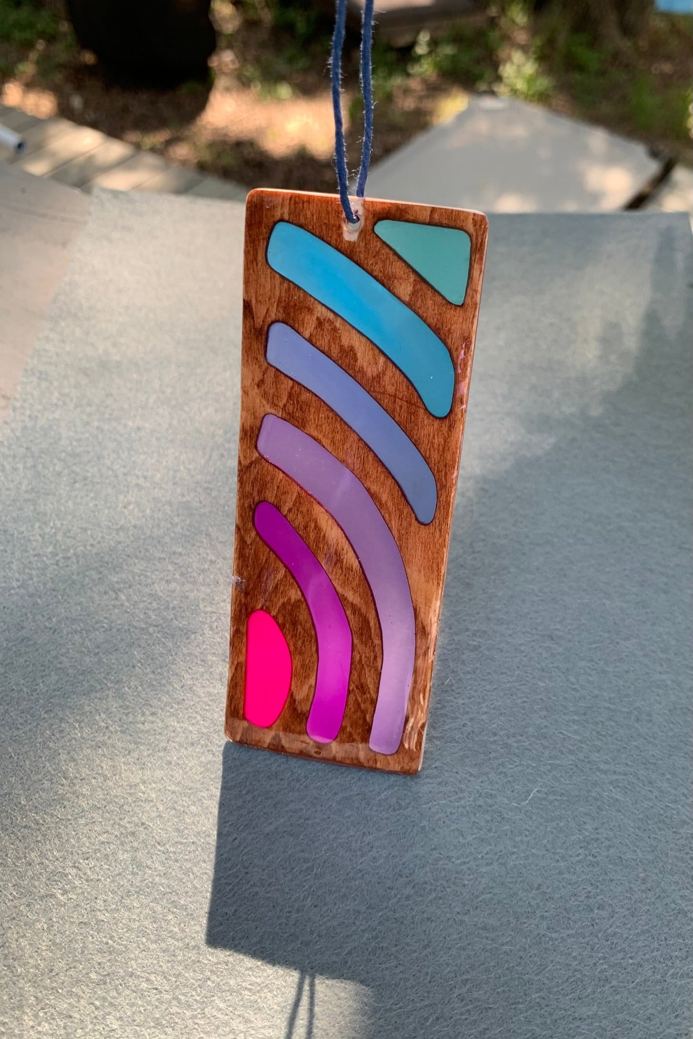 Hand cut wooden bookmark with curved lines emanating an abstract sunset vibe with UV resin translucent colors