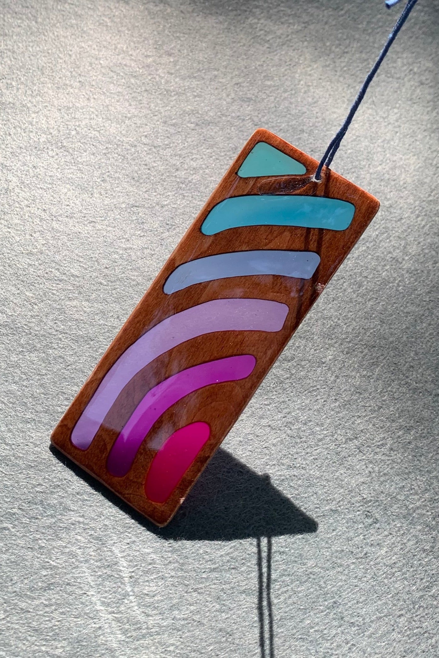 Hand cut wooden bookmark with curved lines emanating an abstract sunset vibe with UV resin translucent colors