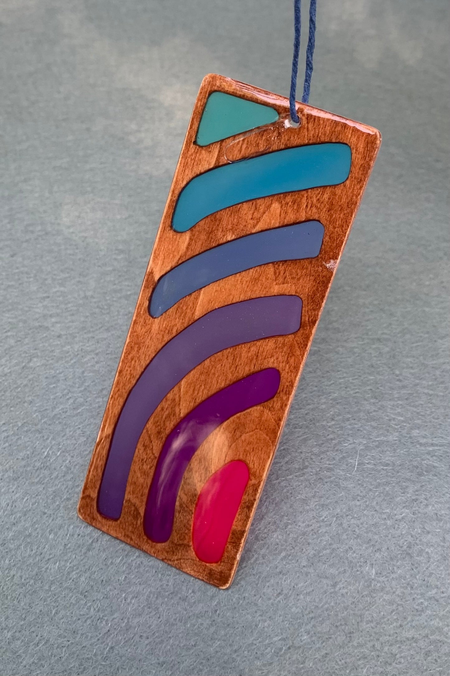 Hand cut wooden bookmark with curved lines emanating an abstract sunset vibe with UV resin translucent colors