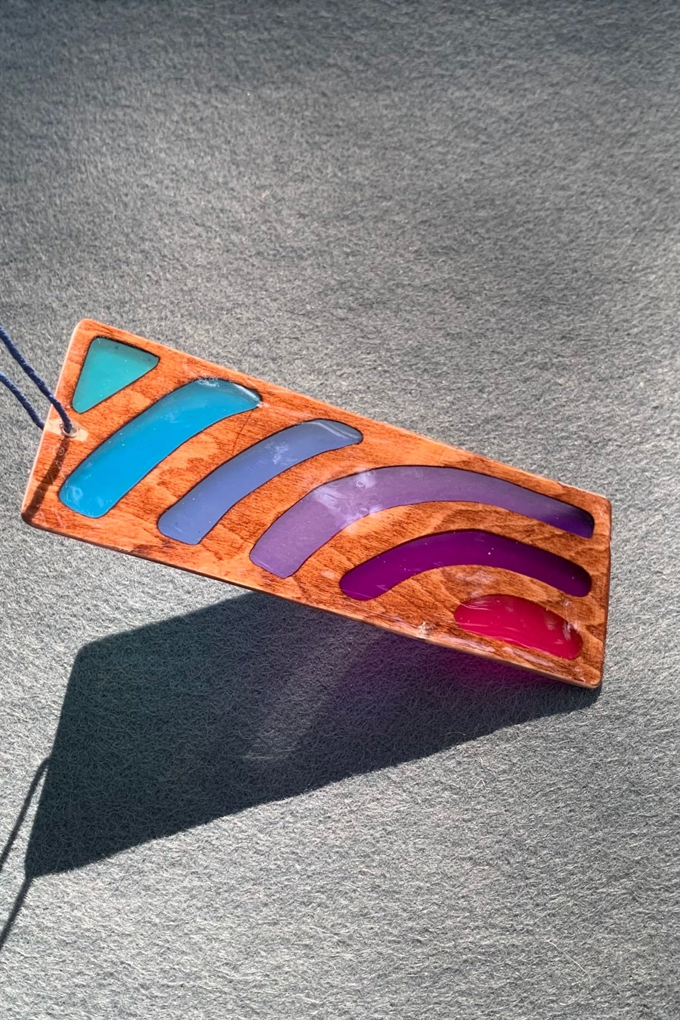 Hand cut wooden bookmark with curved lines emanating an abstract sunset vibe with UV resin translucent colors