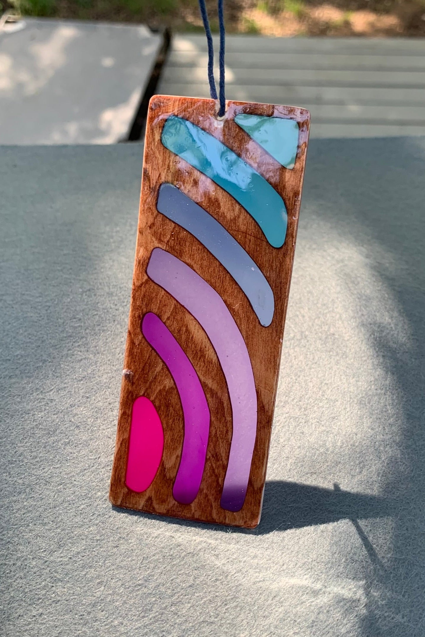 Hand cut wooden bookmark with curved lines emanating an abstract sunset vibe with UV resin translucent colors