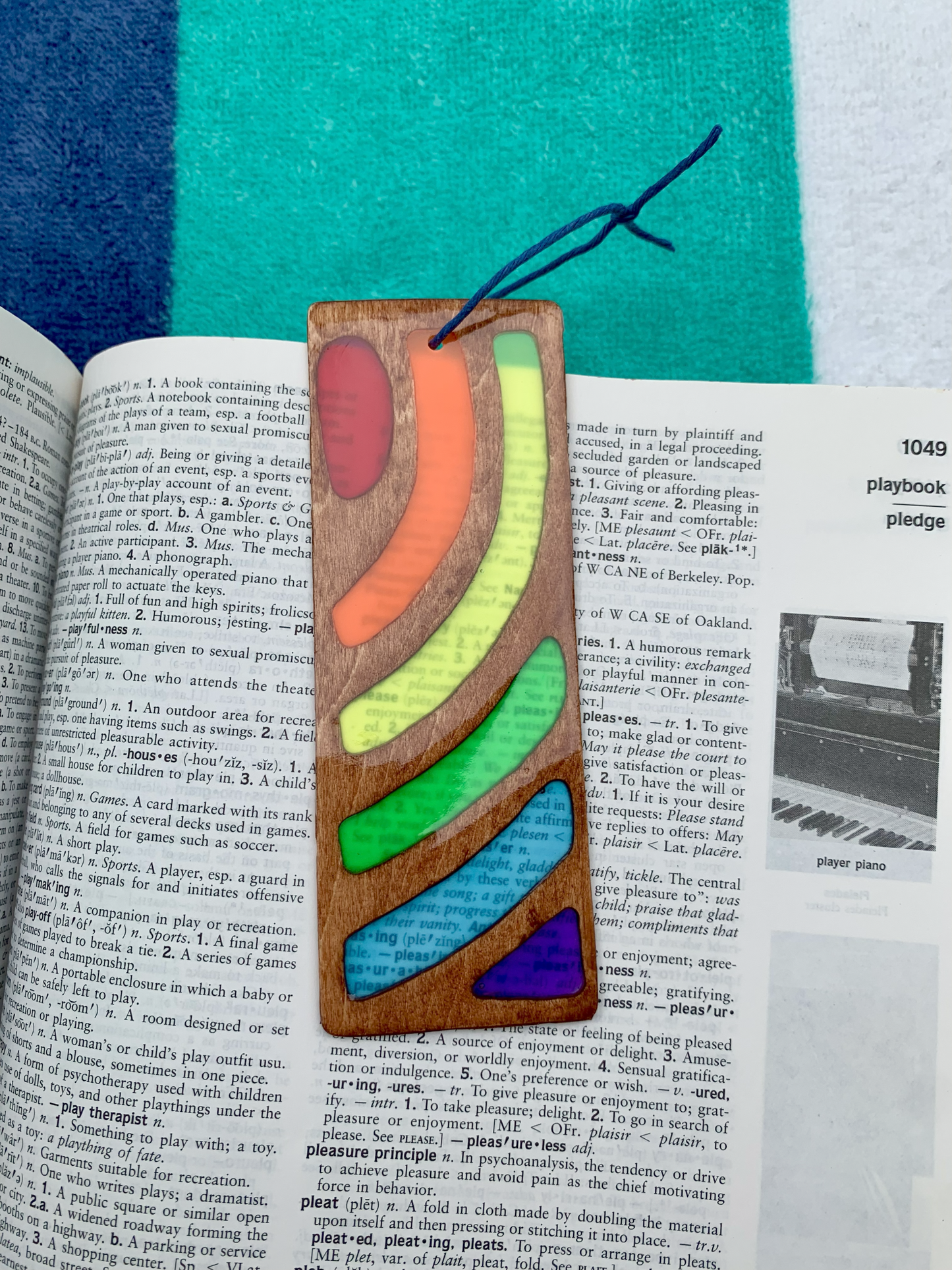 Colorful wooden bookmark on an open book with a multicolored fabric background