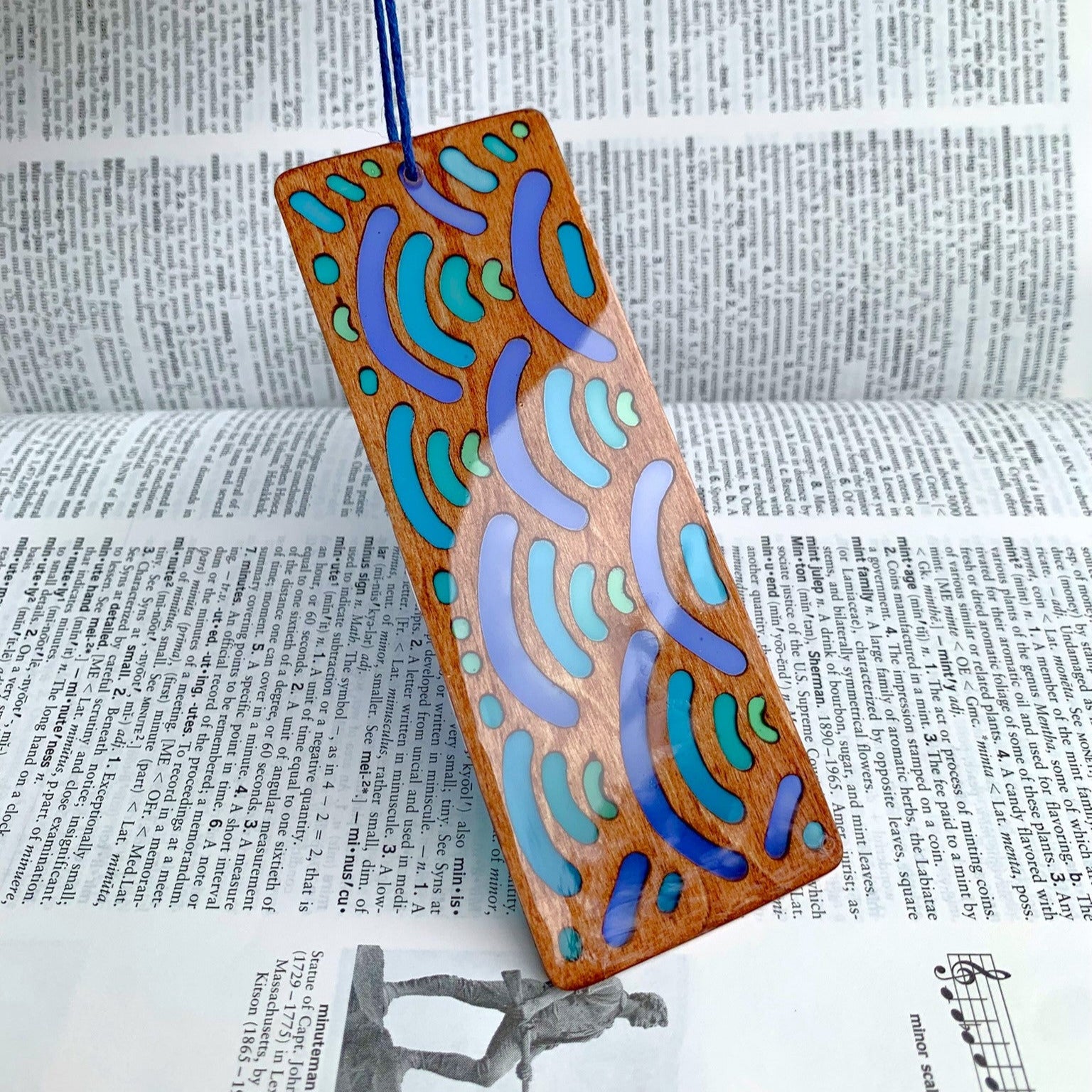 Wooden bookmark with colorful wave pattern on a dictionary background