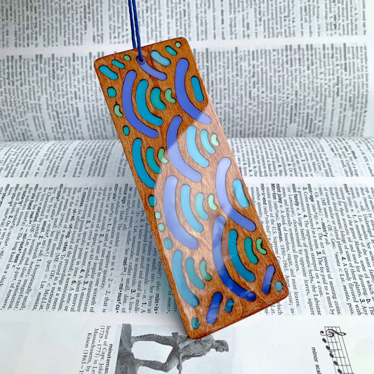 Wooden bookmark with colorful wave pattern on a dictionary background