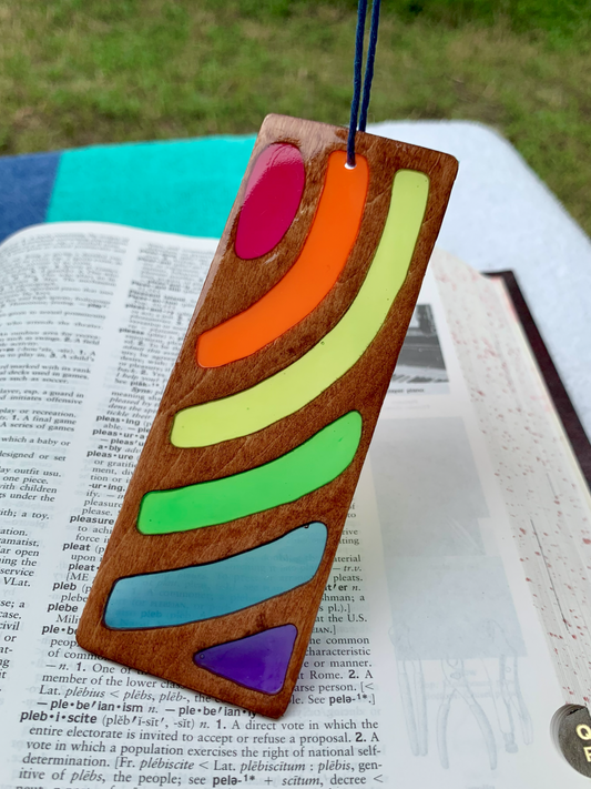Colorful wooden bookmark on an open book with a grassy background